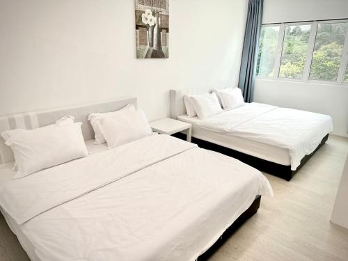two beds in a room with white sheets and pillows at ALVILLA - Jalan Sultan Ismail in Kuala Terengganu