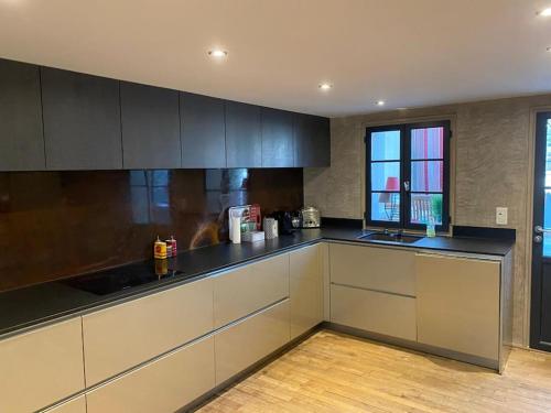 une cuisine avec des armoires blanches et un comptoir noir dans l'établissement Le Grand Mazarin T2, à Aix-en-Provence