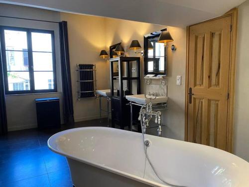 une grande baignoire blanche dans une salle de bain avec une fenêtre dans l'établissement Le Grand Mazarin T2, à Aix-en-Provence