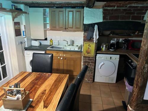 uma cozinha com uma mesa de madeira e um lavatório em Entire 3 bedroom Grade 2 listed, close to town centre em Kent