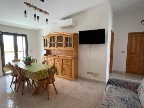 a kitchen with a table with chairs and a television at Caletta Relax by Blu Sardinia in La Caletta