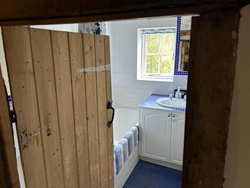 uma casa de banho com uma porta de madeira e um lavatório em Entire 3 bedroom Grade 2 listed, close to town centre em Kent
