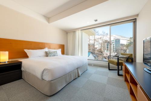 sypialnia z łóżkiem, biurkiem i oknem w obiekcie Chatrium Niseko Japan w mieście Niseko