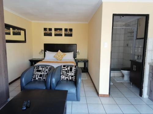 a bedroom with a bed and a chair and a bathroom at Kwena Maribane Lodge in Bronkhorstspruit