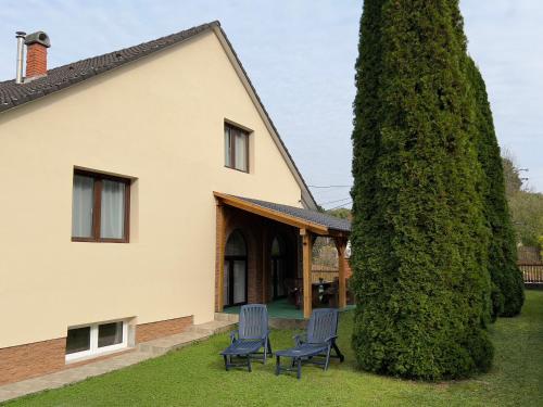 dos sillas frente a una casa con un árbol grande en Kajta-Völgye Guesthouse, Jósvafő, National Park Aggtelek, en Jósvafő