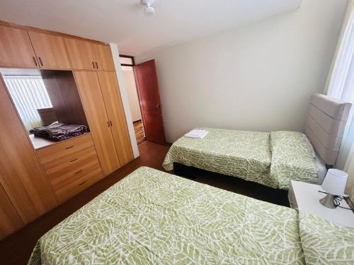 a small room with two beds and a cabinet at Villa Salluzzi Apart Hotel in Tacna