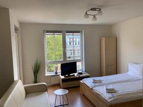 a bedroom with a bed and a tv and a couch at Apartamenty Staromłyńska in Szczecin