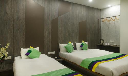 a bedroom with two beds with white sheets and green pillows at Treebo Urban, 1 Km From Railway Station in Surat