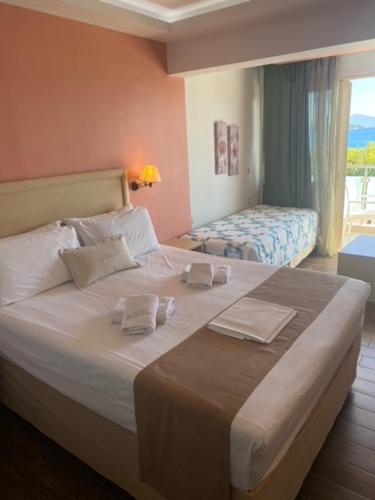a bedroom with a large white bed with a window at Armeno beach hotel in Nydri