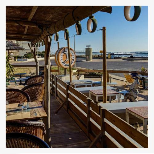 a wooden deck with tables and chairs on the beach at Appartement 1ere ligne piscine terrasse au bord de la plage front de mer avec 6 vélos in Palavas-les-Flots