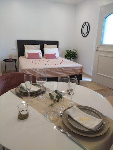 a table with plates and glasses and a bed in a room at Love Room La parenthèse in Saint-Nexans