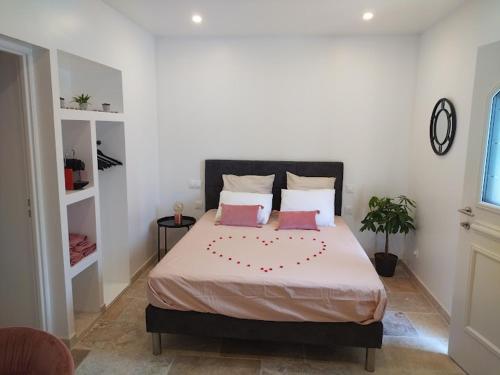 a bedroom with a large bed with two pink pillows at Love Room La parenthèse in Saint-Nexans