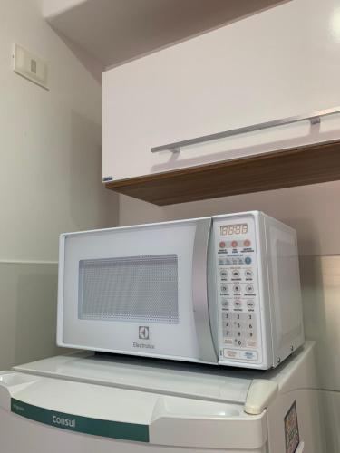 a microwave oven sitting on top of a refrigerator at Apt no Melhor local em Lauro de Freitas in Lauro de Freitas