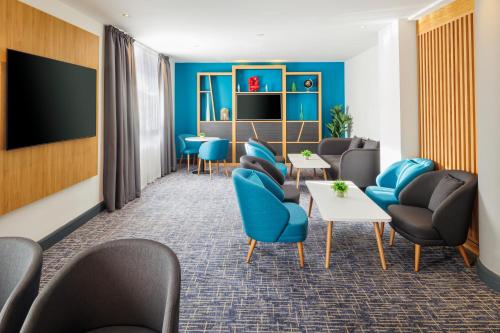 a waiting room with blue chairs and a tv at Holiday Inn High Wycombe M40, Jct.4 by IHG in High Wycombe