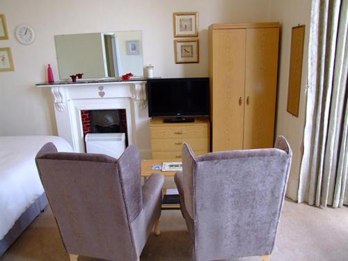 a living room with two chairs and a desk with a television at Redsands Villa in Torquay
