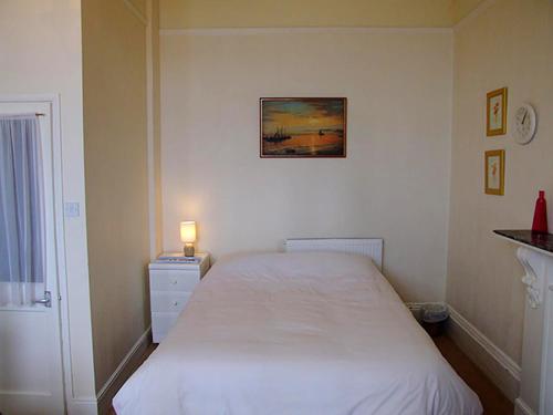 a small bedroom with a white bed and a lamp at Redsands Villa in Torquay