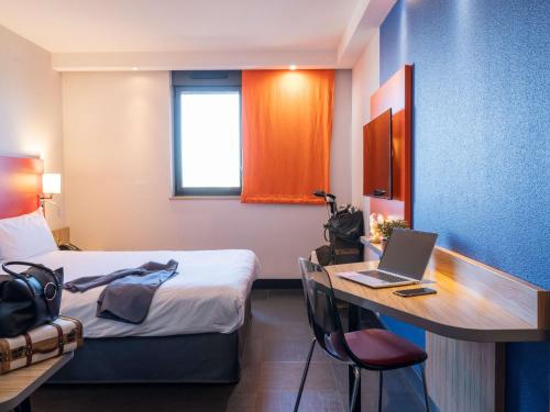 Habitación de hotel con cama y escritorio con ordenador portátil en ibis Styles Romans-Valence Gare TGV en Alixan