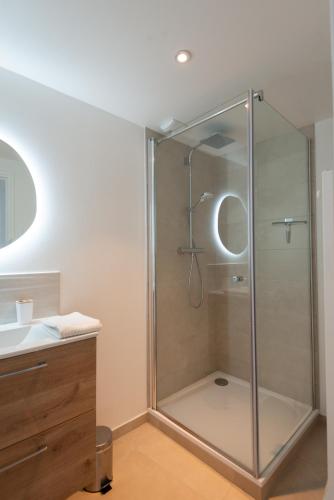une douche en verre dans une salle de bain avec un lavabo dans l'établissement L'Air du Sud - appartement chaleureux Le Tréport, au Tréport