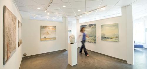 a woman walking in an art gallery looking at paintings at The Grand Hotel in Kennebunk
