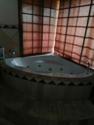 a bath tub in a bathroom with a window at Kwena Maribane Lodge in Bronkhorstspruit