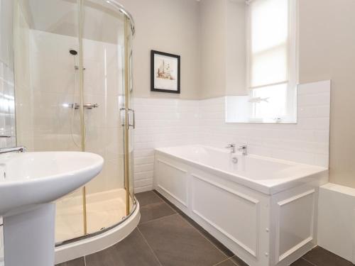 a white bathroom with a shower and a sink at Church View in Grange Over Sands