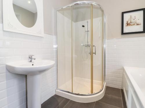 a white bathroom with a shower and a sink at Church View in Grange Over Sands