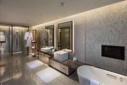a bathroom with a tub and two sinks and a tv at Hilton Quanzhou Riverside in Quanzhou