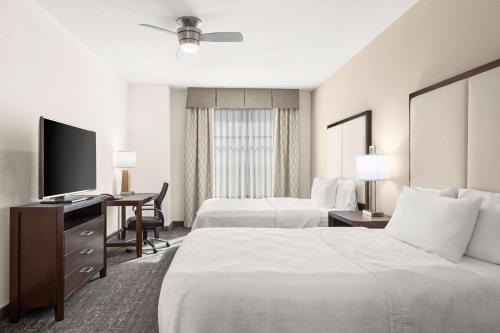 a hotel room with two beds and a desk with a television at Homewood Suites By Hilton San Marcos in San Marcos