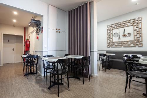 a dining room with black chairs and tables at Guest House Porto Clerigus in Porto
