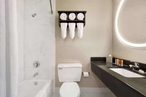 a bathroom with a toilet and a sink and a bath tub at Surfbreak Virginia Beach Oceanfront, Ascend Hotel Collection in Virginia Beach