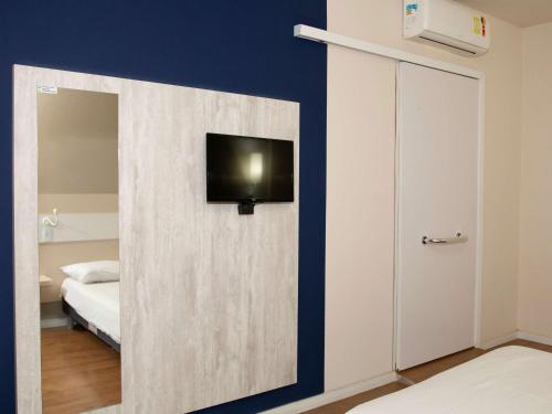 een kamer met een deur en een tv aan de muur bij ibis budget Manhuaçu in Manhuaçu