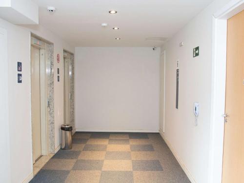 an empty hallway with white walls and a checkered floor at ibis budget Manhuaçu in Manhuaçu