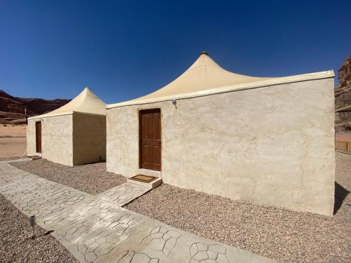 瓦迪拉姆的住宿－Sunrise Colors Camp Wadi rum，沙漠中一座带门的白色建筑