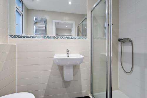 a white bathroom with a sink and a shower at Smart Stay Studio Flat in London