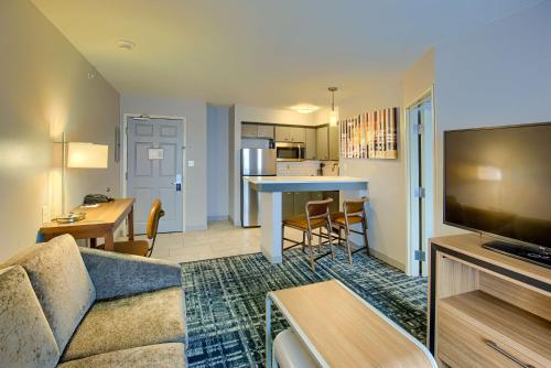 a living room with a couch and a table and a kitchen at Homewood Suites by Hilton South Bend Notre Dame Area in South Bend
