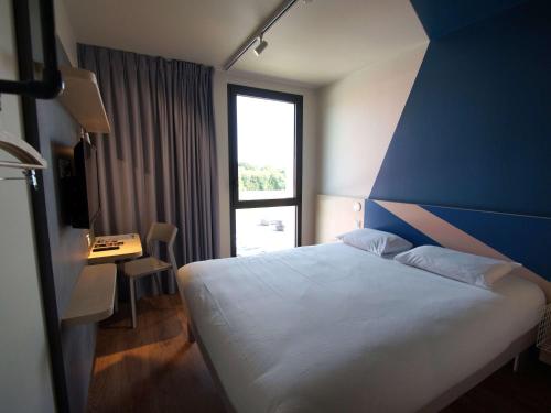 - une chambre avec un lit blanc et un mur bleu dans l'établissement ibis budget Loudéac Vélodrome, à Loudéac