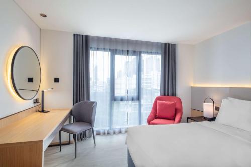 a hotel room with a bed and a desk and a mirror at Best Western Click Sathorn 11 Bangkok in Bangkok