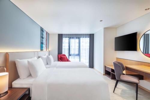 a hotel room with two beds and a tv at Best Western Click Sathorn 11 Bangkok in Bangkok