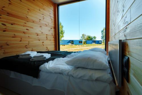 Bett in einem Zimmer mit einem großen Fenster in der Unterkunft Arche Siedlisko Gorodczyno in Narew