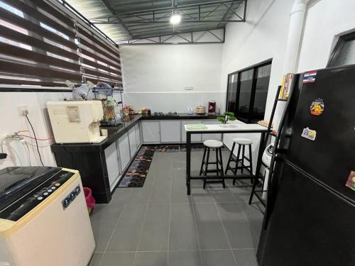 cocina con nevera y mesa con taburetes en ZR HOLDFAST HOMESTAY BUKIT KATIL MELAKA, en Kampong Bukit Beruang