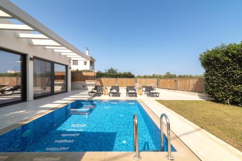 una piscina en el patio trasero de una casa en Oresteia Exclusive Villa, a Sublime Retreat, By ThinkVilla, en Tragaki