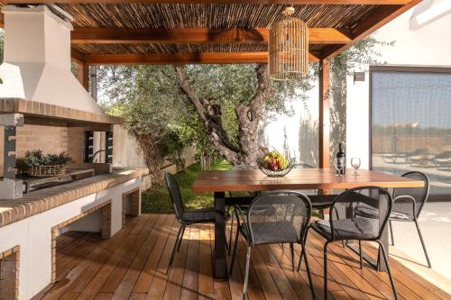 un patio esterno con tavolo e sedie in legno di Oresteia Exclusive Villa, a Sublime Retreat, By ThinkVilla a Tragaki