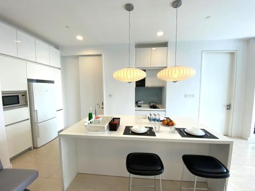 a kitchen with a large white island with black chairs at KLCC Sky Villa Suites Platinum in Kuala Lumpur