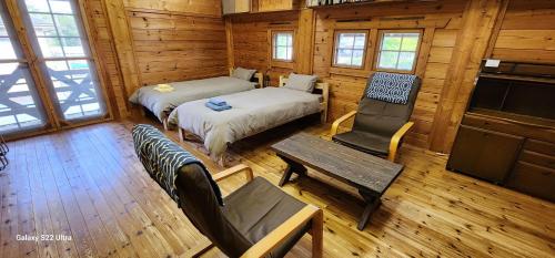 una habitación con 2 camas y una silla en una cabaña en まちなかlodge ほしとたきび Lodge in city Hoshi to Takibi, en Ōmuta