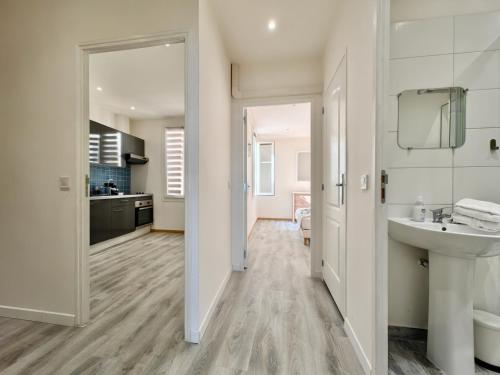 une salle de bain blanche avec un lavabo et un miroir dans l'établissement Foch 3 by Booking Guys, à Villefranche-sur-Mer