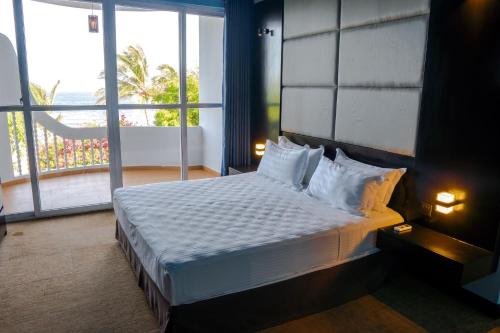 a bedroom with a bed and a large window at Peacock Beach Resort and Spa in Hambantota