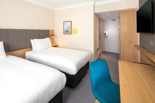 a hotel room with two beds and a blue chair at Holiday Inn High Wycombe M40, Jct.4, an IHG Hotel in High Wycombe