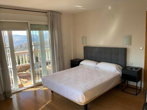 a bedroom with a large bed and a balcony at Hotel Nuevo Palas in Lanjarón