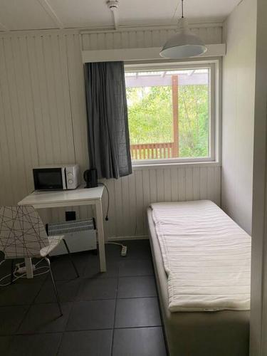 1 dormitorio con cama, escritorio y ventana en Kotimaailma - Hostel Kivikkotie, en Vantaa