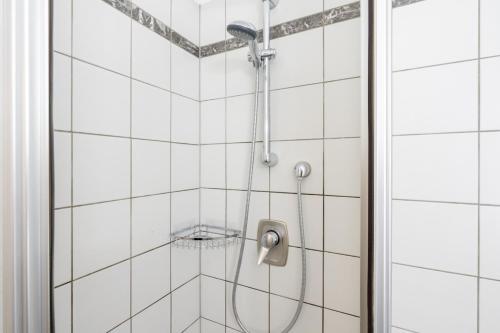 a shower in a bathroom with white tiles at Hotel-Zimmer direkt am See in Gmunden